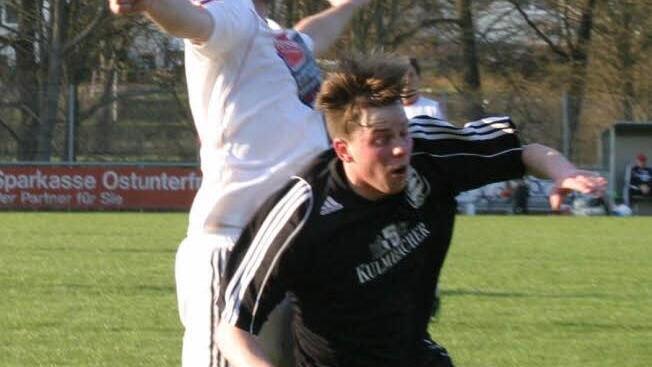 Der Eberner Kim Schütz (dunkles Trikot) wird beim Kopfballduell von hinten gestoßen.