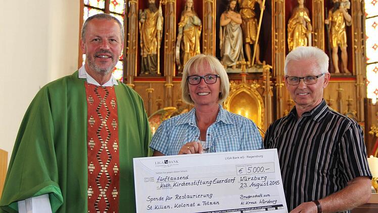 Im Gottesdienst wurde der symbolische Scheck überreicht. Das Bild zeigt (von links) Präses Pater Maximilian und Präfektin Barbara Schebler vom Vorstand der Bruderschaft zum Heiligen Kreuz Würzburg zusammen mit Euerdorfs Kirchenpfleger Burkard Erhard.  Foto: Markus Erhard