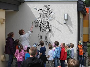 Corinna Zipprich segnet die restaurierte Figur des hl. Sebastian an der Außenfassade des Stangenrother Kindergartens. Foto: privat