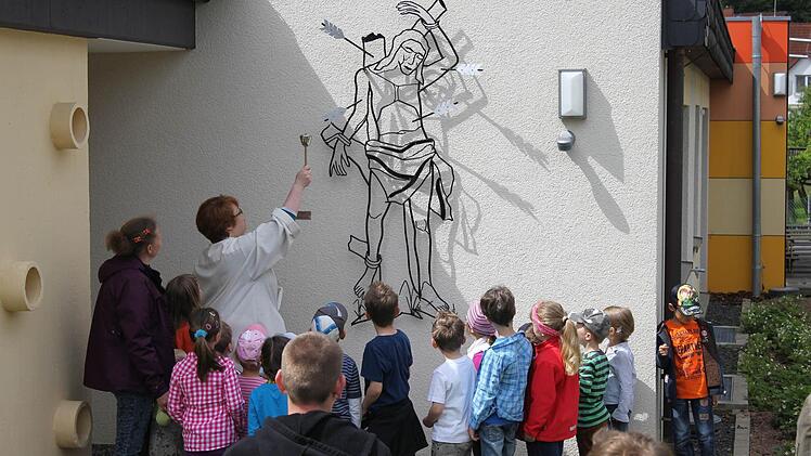 Corinna Zipprich segnet die restaurierte Figur des hl. Sebastian an der Außenfassade des Stangenrother Kindergartens. Foto: privat
