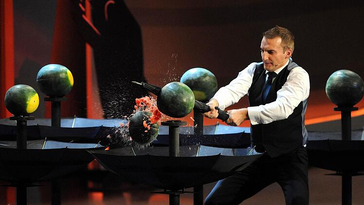 Wettkandidat Milan Zivojinovic teilt am 03.11.2012 in der ZDF-Show &laquo;Wetten, dass..?&raquo; in der &Ouml;VB-Arena in Bremen bei der "Wassermelonen-Wette" Melonen mit einem Regenschirm. Foto: Ingo Wagner/dpa