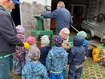 Interessiert schauen die Kinder beim Pressen der selbst gesammelten Äpfel zu.
