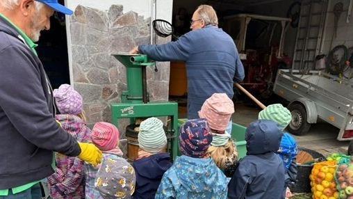 Interessiert schauen die Kinder beim Pressen der selbst gesammelten Äpfel zu.