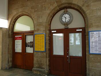 Der Eingang zum ehemaligen Bahnhofsbistro ist verschlossen, die Scheiben sind mit Papier abgeklebt. Darauf angebrachte Fotos lassen erahnen, wie schön der dahinter liegende Jugendstilraum ist. Foto: Ramona Popp