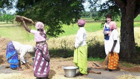Die Asphaltstraße dient den Frauen als Untergrund beim Dreschen von Reis.