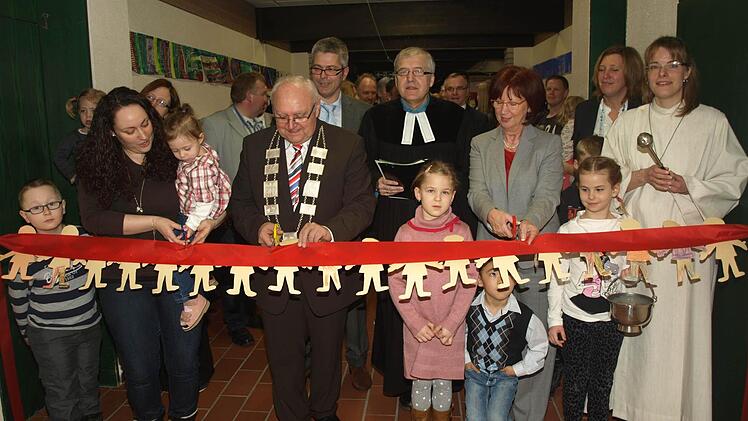Bürgermeister Siegfried Erhard setzt die Schere an. Symbolisch zerschnitt unter anderem er das Band zwischen neuen und alten Räumen im Oerlenbacher Kindergarten.