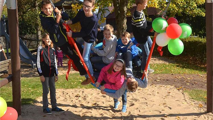 Pfarrer Karl-Theodor Mauer segnete die vom Gartenbauverein und Kleiderbasarteam für 3000 Euro gestiftete Nestschaukel, die gleich darauf von den Reither Kindern in Beschlag genommen wurde. Foto: Peter Rauch