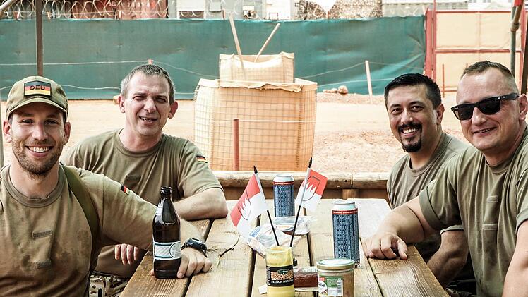 Der Frankenstammtisch in der W&uuml;ste ist sonntags ein beliebter Treffpunkt der Soldaten. Der Ansbacher Michl R. (vorne rechts) genie&szlig;t mit seinen Kameraden Markus R. (hinten rechts), Michael R. (hinten links) und Stefan J. (vorne links) die Spezialit&auml;ten aus der Heimat, die die Familien &uuml;ber Feldpost schicken.  Fotos: Enric Boixad&oacute;s