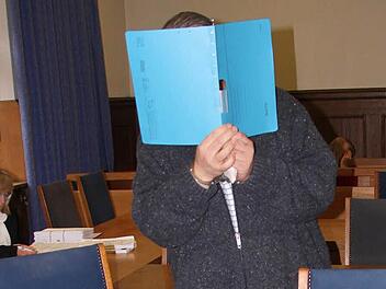Stephan R. verdeckt sein Gesicht mit einem Schnellhefter.  Foto: Groscurth