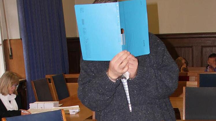 Stephan R. verdeckt sein Gesicht mit einem Schnellhefter.  Foto: Groscurth