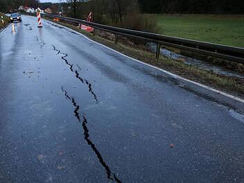 Nicht zu übersehen sind die Risse im Asphalt der Staatsstraße 2188 (im Hintergrund Zoggendorf). Zwischen der Straße und der etwa fünf Meter tiefer fließenden Leinleiter (rechts) werden derzeit    Kanalrohre verlegt.   Wie lange die Sperrung der Straße dauern wird ist noch nicht  bekannt.  Foto:  Barbara Herbst