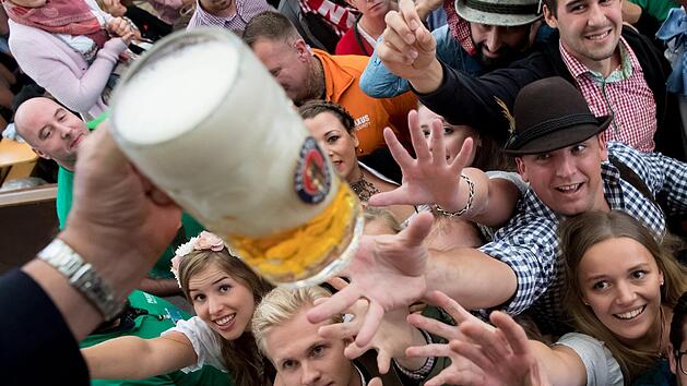 München: Besucher freuen sich beim Auftakt zum Oktoberfest über ihr erstes Bier. Ein Liter Bier kann im Laden 60 Cent oder elf Euro kosten. Der Durchschnittspreis ist dieses Jahr gestiegen. Foto: Sven Hoppe/dpa