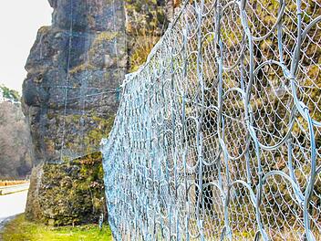 Stahlnetze umschließen die Felsen (im Hintergrund), mächtige Stahlzäune wurden am Böschungsfuß des angrenzenden Hangs angebracht, um herabfallende Steine vor der Fahrbahn abzufangen. Sicherungsmaßnahmen, die bei Wonsees vorgenommen wurden.Fotos: Alexander Hartmann