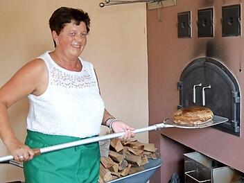 Birgit Heilmann holt das erste selbstgebackene Brot aus dem Ofen des Mühlendorfer Backhauses. Foto: Andrea Spörlein