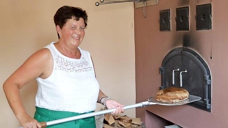 Birgit Heilmann holt das erste selbstgebackene Brot aus dem Ofen des Mühlendorfer Backhauses. Foto: Andrea Spörlein