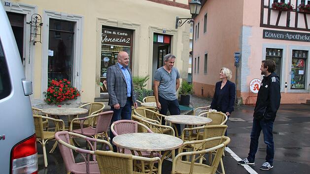 Michael Kastl, Arno Reuscher, Christine Martin und Johannes Wolf sehen sich die Außenbewirtschaftung der Eisdiele auf einem Parkplatz an. Durch die flexible Nutzung des öffentlichen Raums sollen sie und andere Gastronomiebetriebe sich am Wochenende ausbreiten können. Foto: Thomas Malz