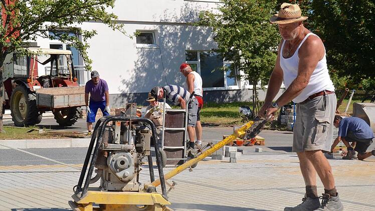 Rüttelarbeit: Norbert Straub ist gelernter Straßenbauer und mit der Rüttelmaschine zu Gange. Im Hintergrund arbeiten weitere Helfer. Foto: Kathrin Kupka-Hahn