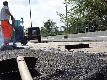 Arbeiter tragen eine Schutzschicht auf die Fahrbahn auf. Foto: Arkadius Guzy