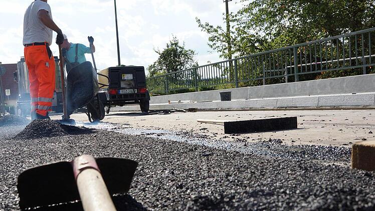 Arbeiter tragen eine Schutzschicht auf die Fahrbahn auf. Foto: Arkadius Guzy