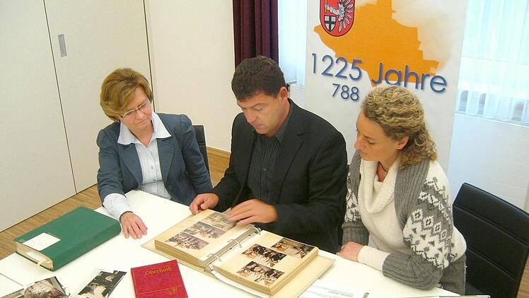 Ein Teil des Arbeitskreises, der das Jubiläum vorbereitet: Chefsekretärin Ursula Stark, Bürgermeister Carsten Joneitis und Archivpflegerin Barbara Spies (v.l.) sichten alte Fotoalben, Postkarten und Chroniken. Foto: Anette Schreiber