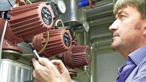 Uwe Täuber liest anhand eines Messgeräts auf seinem Handy ab, wie viel Strom die Umwälzpumpen im Keller der Thurnauer Schule verbrauchen. Foto: Katharina Müller-Sanke