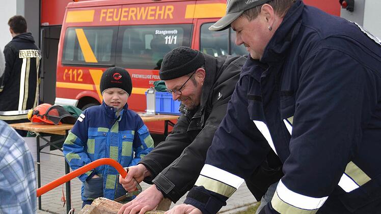 Peter Kleinhenz ist hier dabei, eine 300 Gramm schwere Holzscheibe abzusägen. Sohn Anton guckt etwas ungläubig zu, während Feuerwehrmann Manfred Erb den Stamm hält. Foto: Kathrin Kupka-Hahn