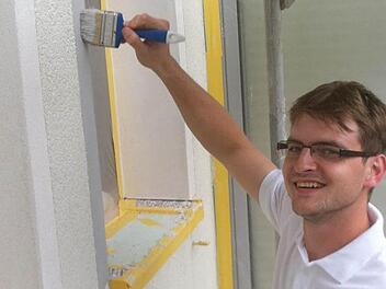 Das Malerhandwerk wurde ihm schon in die Wiege gelegt: Der frisch gebackene Malergeselle Florian Döpfner streicht auf einer Baustelle in Schwarzach die Faschetten eines Fensters.