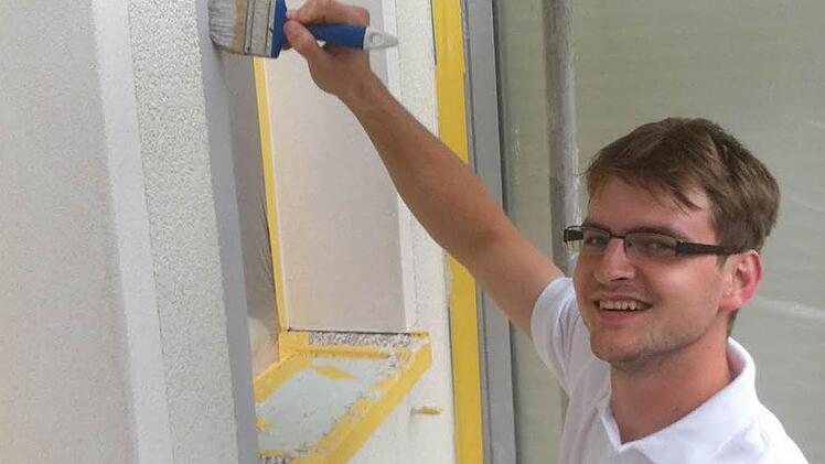 Das Malerhandwerk wurde ihm schon in die Wiege gelegt: Der frisch gebackene Malergeselle Florian Döpfner streicht auf einer Baustelle in Schwarzach die Faschetten eines Fensters.