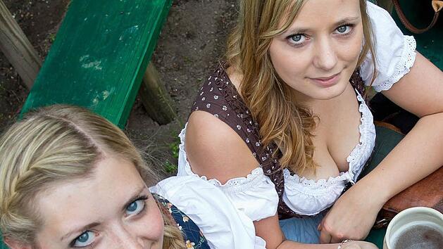 Junge Bergbesucherinnen sto&szlig;en auf einem traditionellen Bierkellern der Bergkirchweih mit einem Tonkrug Bier an. Foto: Daniel Karmann/dpa