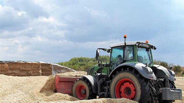 Nach dem Abladen der Mais-H&auml;ckselmasse verdichten Schlepper den Haufen zur sp&auml;teren Lagerung. Foto: Sigismund von Dobsch&uuml;tz
