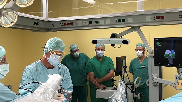 Während der Chirurg mit dem Roboterarm am offenen Gelenk fräst, überwacht ein Computer  die OP und hilft bei der hochpräzisen Arbeit mit.  Am Donnerstag machte sich auch SPD-MdB Andreas Schwarz (Mitte) eine Eindruck vom "Mako"-System. Foto: Klinikum Forchheim