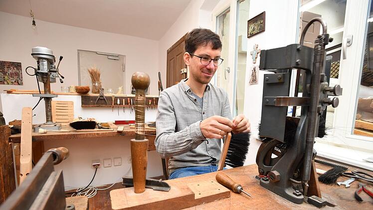 Kilian Schumm verbindet Handfeger-Rücken und Rosshaar-Bündel mit Draht. Foto: Ronald Rinklef