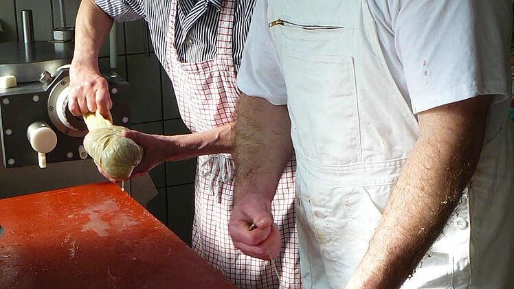 Helmut Baumer (hinten) und Matthias Kummer beim Abfüllen des weißen Presssacks in die Naturdärme.