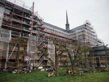 Die Bamberger Klosterkirche St. Michael ist von Gerüsten umgeben, während der Sanierung, umgeben von Bäumen auf einer Wiese.