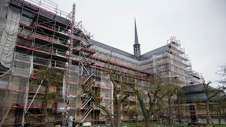 Die Bamberger Klosterkirche St. Michael ist von Gerüsten umgeben, während der Sanierung, umgeben von Bäumen auf einer Wiese.
