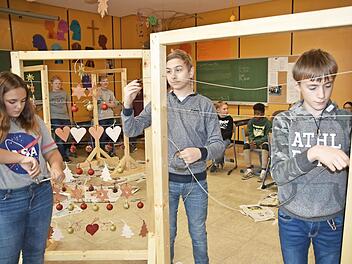 Celine Sch&ouml;n, Artur Fux und Eric Kretzschmar ziehen beim letzten Dekorahmen die Drahtaufh&auml;ngung ein. Foto: Uschi Prawitz