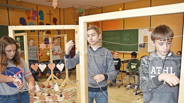 Celine Sch&ouml;n, Artur Fux und Eric Kretzschmar ziehen beim letzten Dekorahmen die Drahtaufh&auml;ngung ein. Foto: Uschi Prawitz