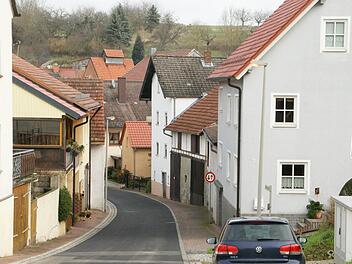 Schmal und abschüssig, mit einer engen Einmündung in die Hauptstraße, das ist die Bischof-Pflaum-Straße im Eltmanner Stadtteil Lembach, hier von Kirchaich kommend in Richtung Ortsmitte. Die Anwohner wünschen sich, dass die Tempobeschränkung für alle Fahrzeuge gelten und auch kontrolliert werden soll.  Foto: Sabine Weinbeer