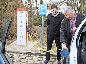 Christian Ziegler von der Bayernwerk AG und Bürgermeister Jürgen Hennemann (rechts) "betanken" ein E-Mobil, das der Stromkonzern der Stadt für einige Wochen leihweise zur Verfügung stellt. Fotos: Ralf Kestel