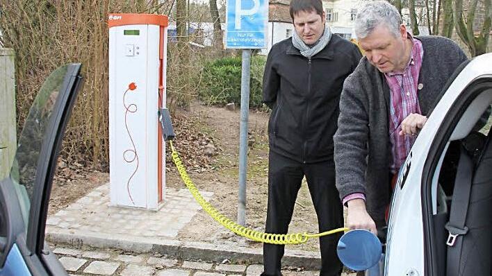 Christian Ziegler von der Bayernwerk AG und Bürgermeister Jürgen Hennemann (rechts) "betanken" ein E-Mobil, das der Stromkonzern der Stadt für einige Wochen leihweise zur Verfügung stellt. Fotos: Ralf Kestel