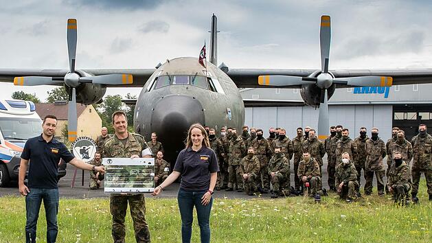 Scheckübergabe von Oberstleutnant Sascha André Zander (Mitte) an Caterina Hertweck und Julian Knaup vom Wünschewagen Franken/Oberpfalz vor der C-160 Transall, dem Wünschewagen sowie Soldaten der Inspektion. Foto: Bundeswehr/Rippstein