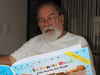 Autor Mac Pfeifer mit seinem Kinderbuch "Ein bunter Hund geht durch die Stadt". Foto: Thomas Mäuser