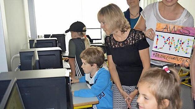 Während die Kinder verschiedene Programme an den neuen Computern ausprobieren, sehen ihnen Schulleiterin Rosmarie Wagner (l.) und Claudia Marie Escherich (mit Bild) über die Schulter. Foto: Larissa Händel