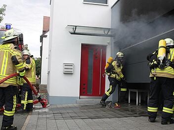 Mit Atemschutz öffnen die Feuerwehrleute  das Garagentor. Foto: Oswald