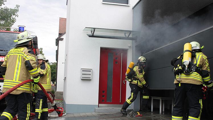 Mit Atemschutz öffnen die Feuerwehrleute  das Garagentor. Foto: Oswald