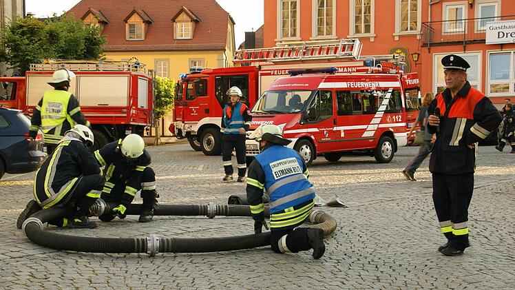 Der federführende Kommandant Uwe Hümmer (rechts) erläuterte per Mikrofon den Zuschauern die einzelnen Maßnahmen der Feuerwehrleute. Hier entsteht der "Rahmen" des Dekontaminierungsbeckens.