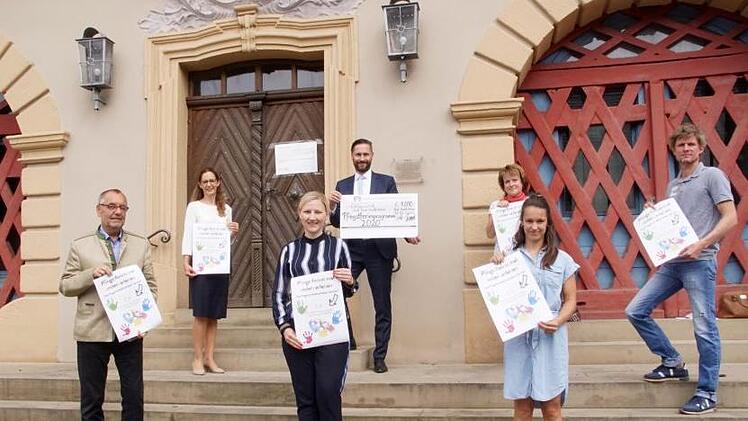 Bürgermeister Jürgen Kohmann, Anna Maria Schneider vom Kur- und Tourismus-Service sowie weitere Mitwirkende wünschen den Kindern viel Freude mit dem unter besonderen Vorzeichen entstandenen 16. Pfingstferienprogramm der Stadt Bad Staffelstein.  Fotos: Mario Deller