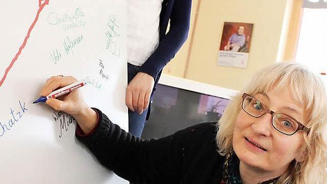 Birgit Sauerschell (rechts) unterschreibt auf der großen Spendentafel von "Franken helfen Franken". Foto: Tobias Kindermann
