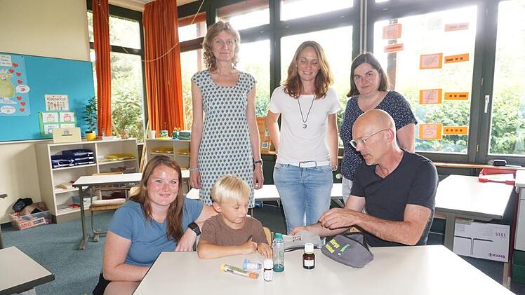 Simon Kirchner und sein Klassenlehrer Georg Schäfer kontrollieren, ob der Inhalt seiner Notfall-Allergie-Tasche auch vollständig ist. Mit im Bild von links: Maria Seiler (Mittagsbetreuung), Rektorin Jutta Spee, Melanie Kirchner und Bürgermeisterin Sonja Reubelt.  Fotos: Marion Eckert