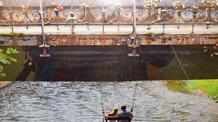 Liebespaar auf der Schaukel unter der Brücke der Liebesschlösser